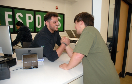 A student arm wrestles Ali in the copy centre