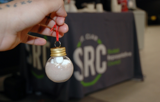 A to go hot chocolate held in front of the table, SRC logo on the tablecloth in the background