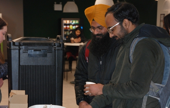 Two students take their turn at the hot chocolate table
