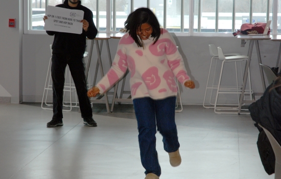 A student hops on one leg while Pratham stands in the background