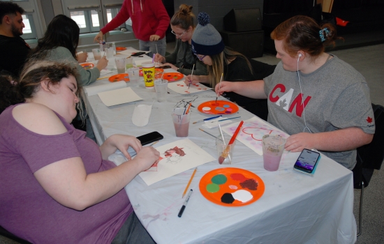 A table full of students working on their paintings