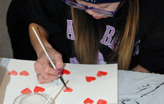 A student paints hearts on her paper
