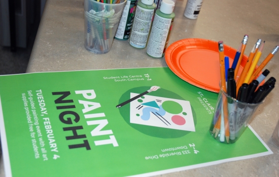 A poster for the event sits on a table with art supplies around it