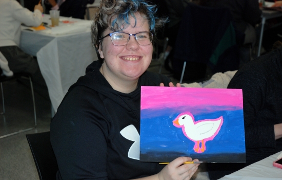 A student shows off their painting 