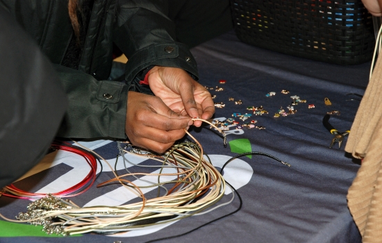 Students make charm jewellery at the table