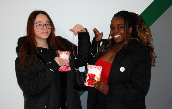 Two students hold up their charm necklaces and other treats