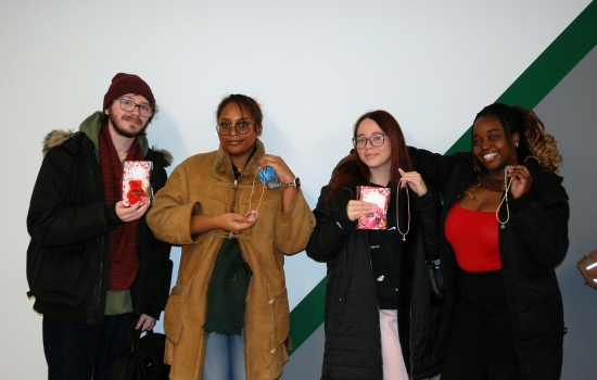 Four students hold up their charm necklaces and other treats