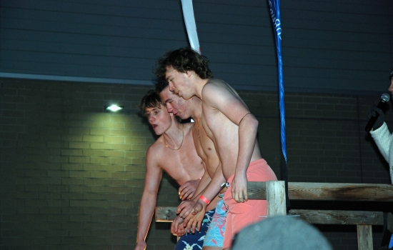 Three shirtless plungers prepare to jump into the icy waters
