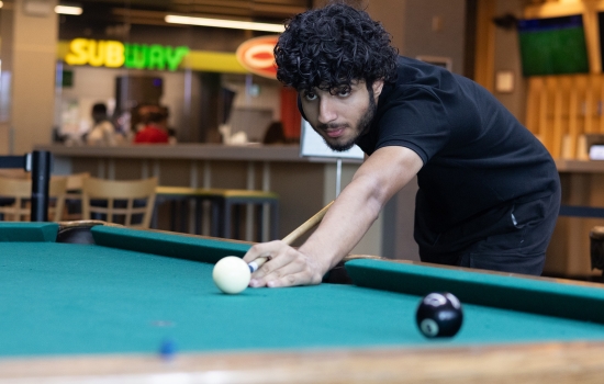 A student lines up his pool shot