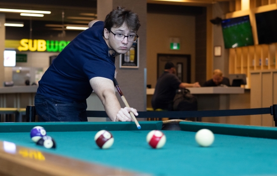 A student lines up his pool shot