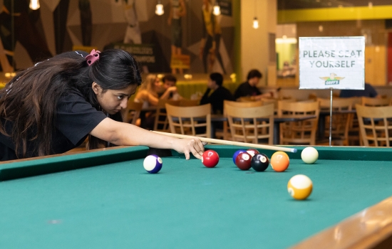 A student lines up her pool shot