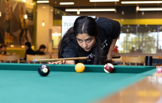 A student lines up her pool shot