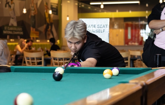 A student lines up his pool shot