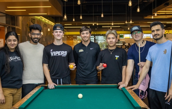 Participants of the Pool Tournament pose behind the pool table