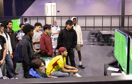 Students play FIFA in the Nexus as a crowd watches