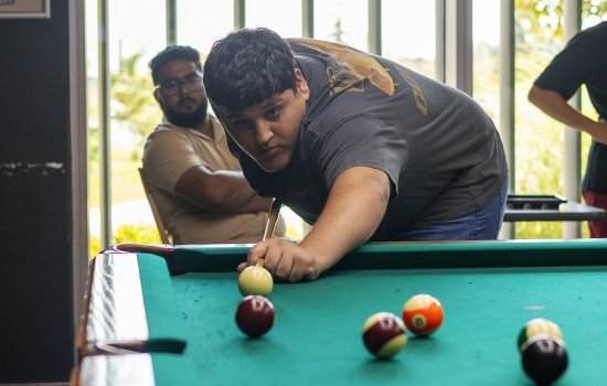 A student lines up his pool shot