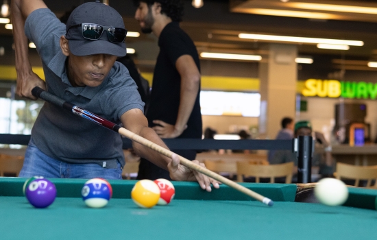A student lines up his pool shot