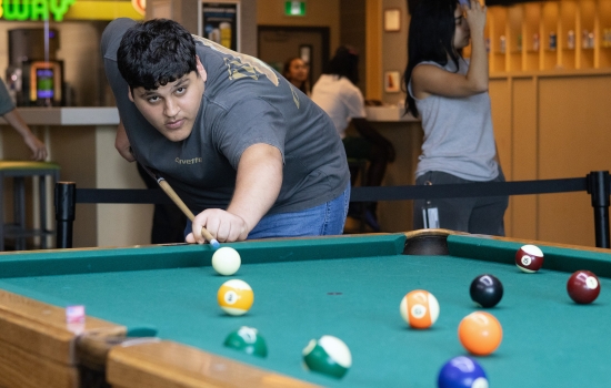 A student lines up his pool shot