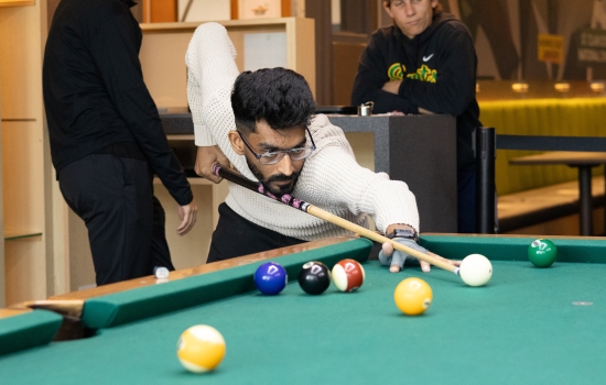 A student lines up his pool shot