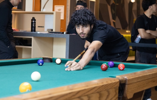 A student lines up his pool shot