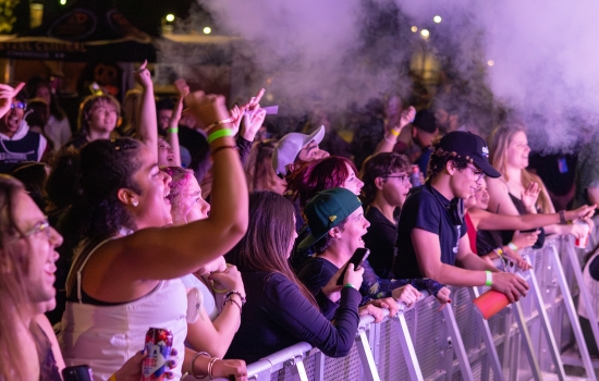 A concert crowd in front of a stage barrier 
