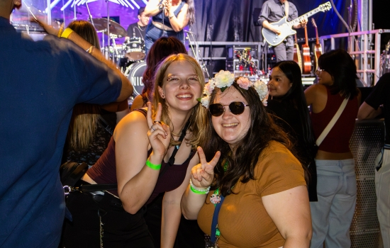 Two students give peace signs and smile at the camera