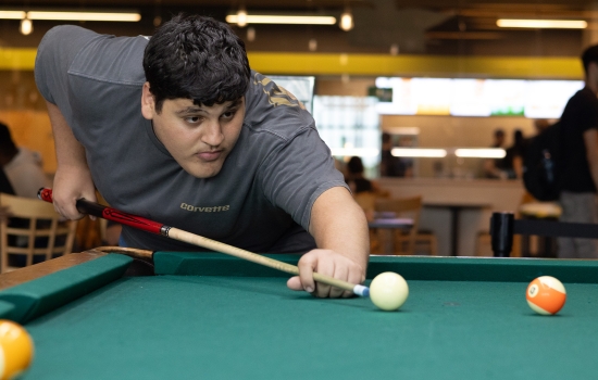A student lines up his pool shot