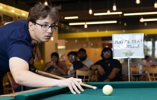 A student lines up his pool shot