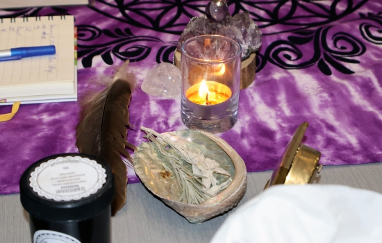 Various items on the table including a feather, a candle and crystals. 