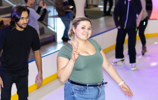 A student smiles and flashes a peace sign for the camera while skating the rink