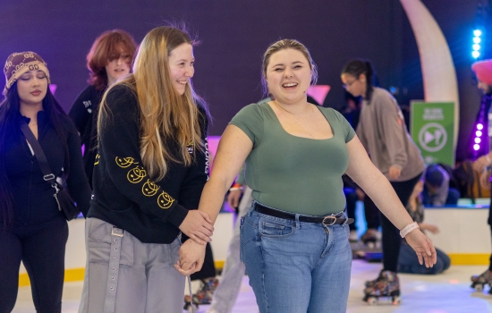 Students help each other balance on skates