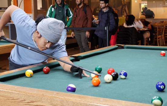 A student leans in for their pool shot in Griff's