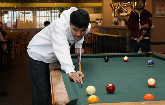 A student leans in for their pool shot in Griff's