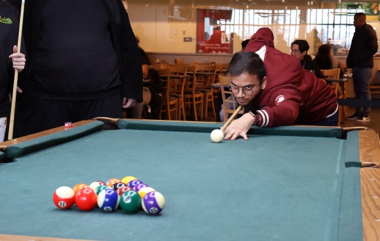 A student leans in for their pool shot in Griff's