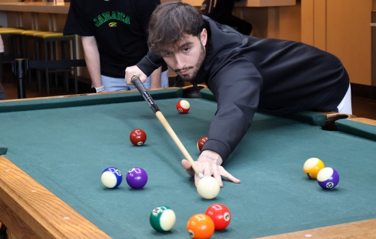 A student leans in for their pool shot in Griff's