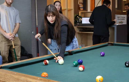 A student leans in for their pool shot in Griff's