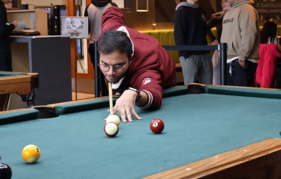 A student leans in for their pool shot in Griff's