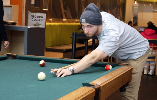 A student leans in for their pool shot in Griff's