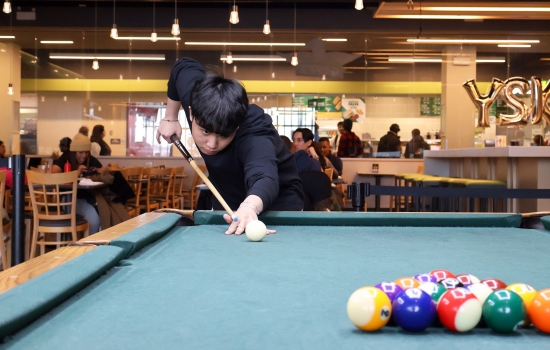 A student leans in for their pool shot in Griff's