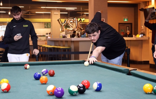 A student leans in for their pool shot in Griff's
