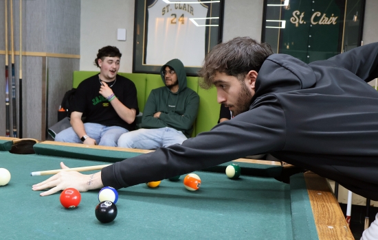A student leans in for their pool shot in Griff's