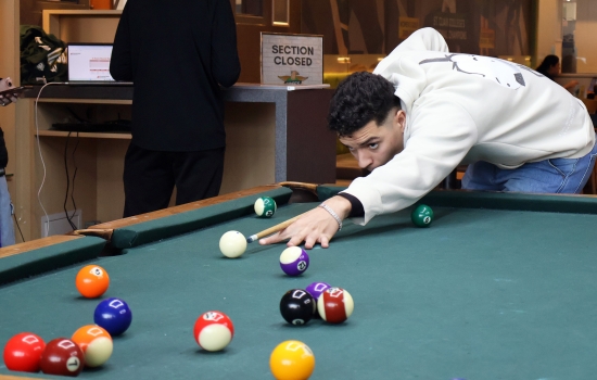 A student leans in for their pool shot in Griff's