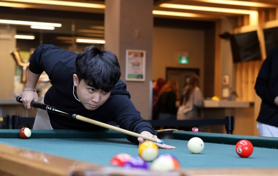 A student leans in for their pool shot in Griff's