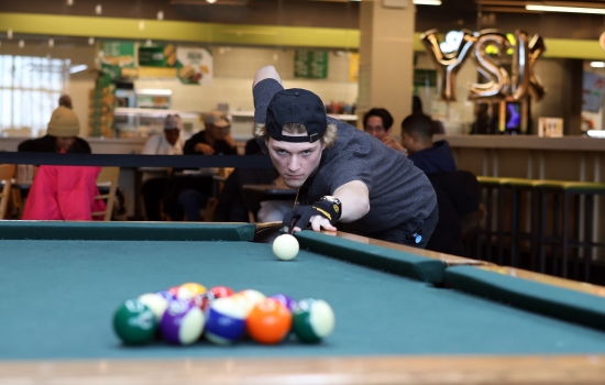 A student leans in for their pool shot in Griff's