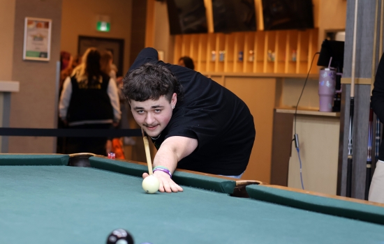 A student leans in for their pool shot in Griff's