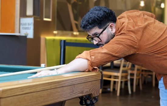 A student leans in for their pool shot in Griff's