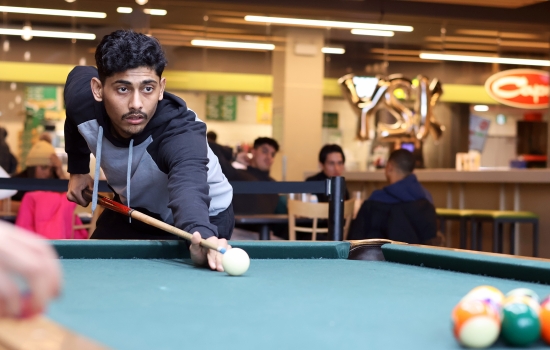 A student leans in for their pool shot in Griff's