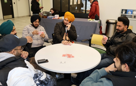 6 students play a game of cards at a round table