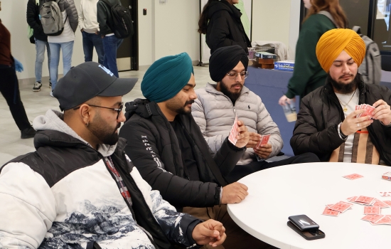 4 students play a game of cards at a round table
