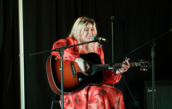 A contestant sings and plays guitar on the SLC stage